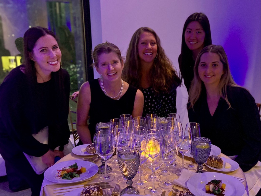 A group of women are sitting at a table with plates of food and wine glasses.