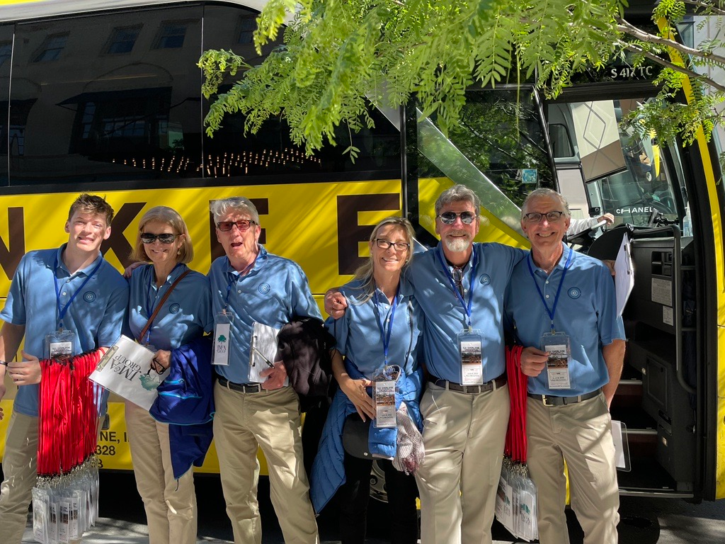 A group of people are posing for a picture in front of a yellow bus.