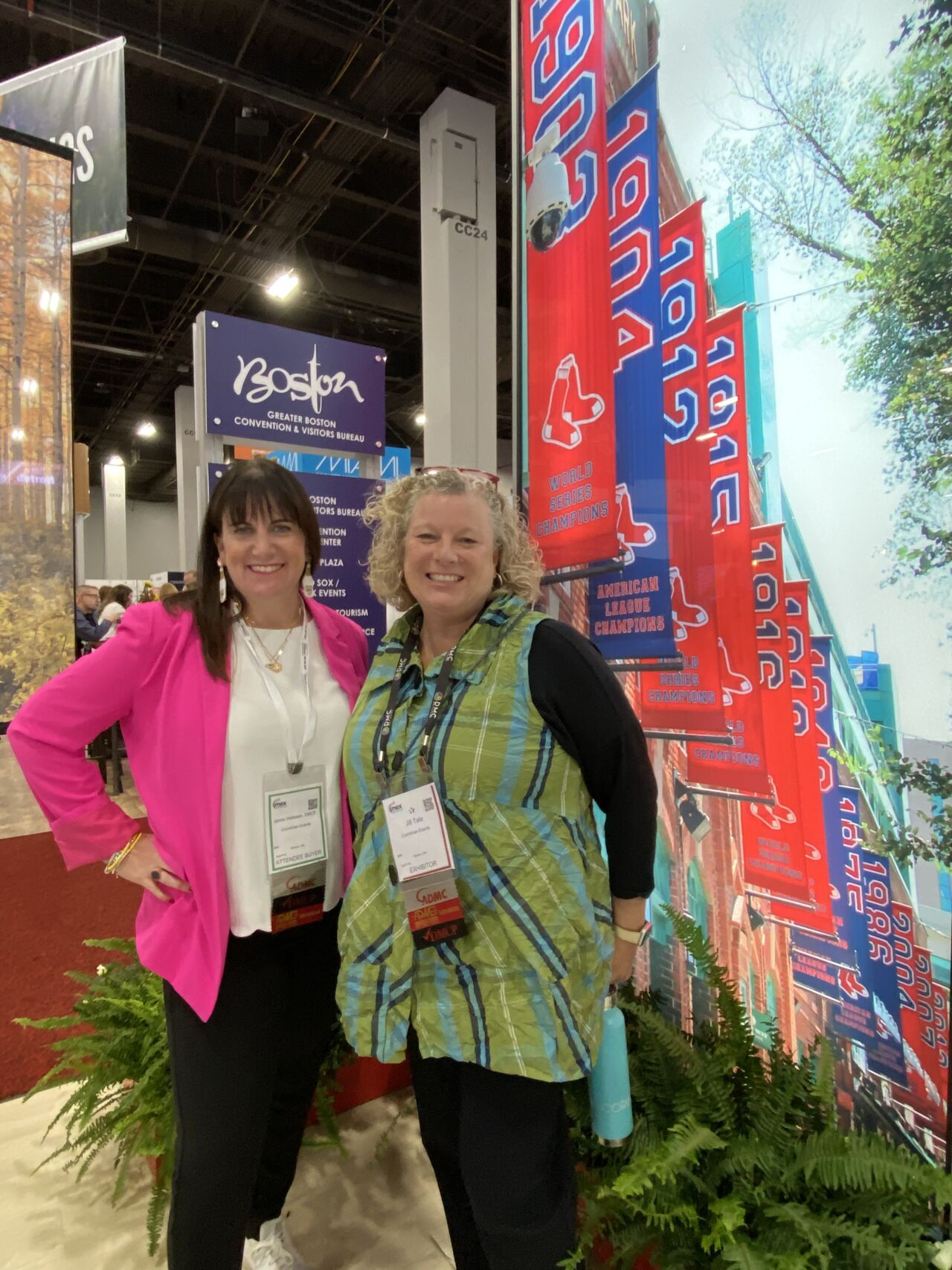 Two women are posing for a picture in front of a boston sign.