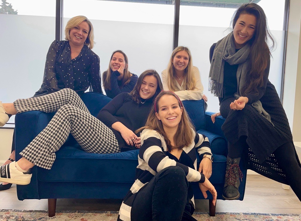 A group of women are posing for a picture while sitting on a blue couch.