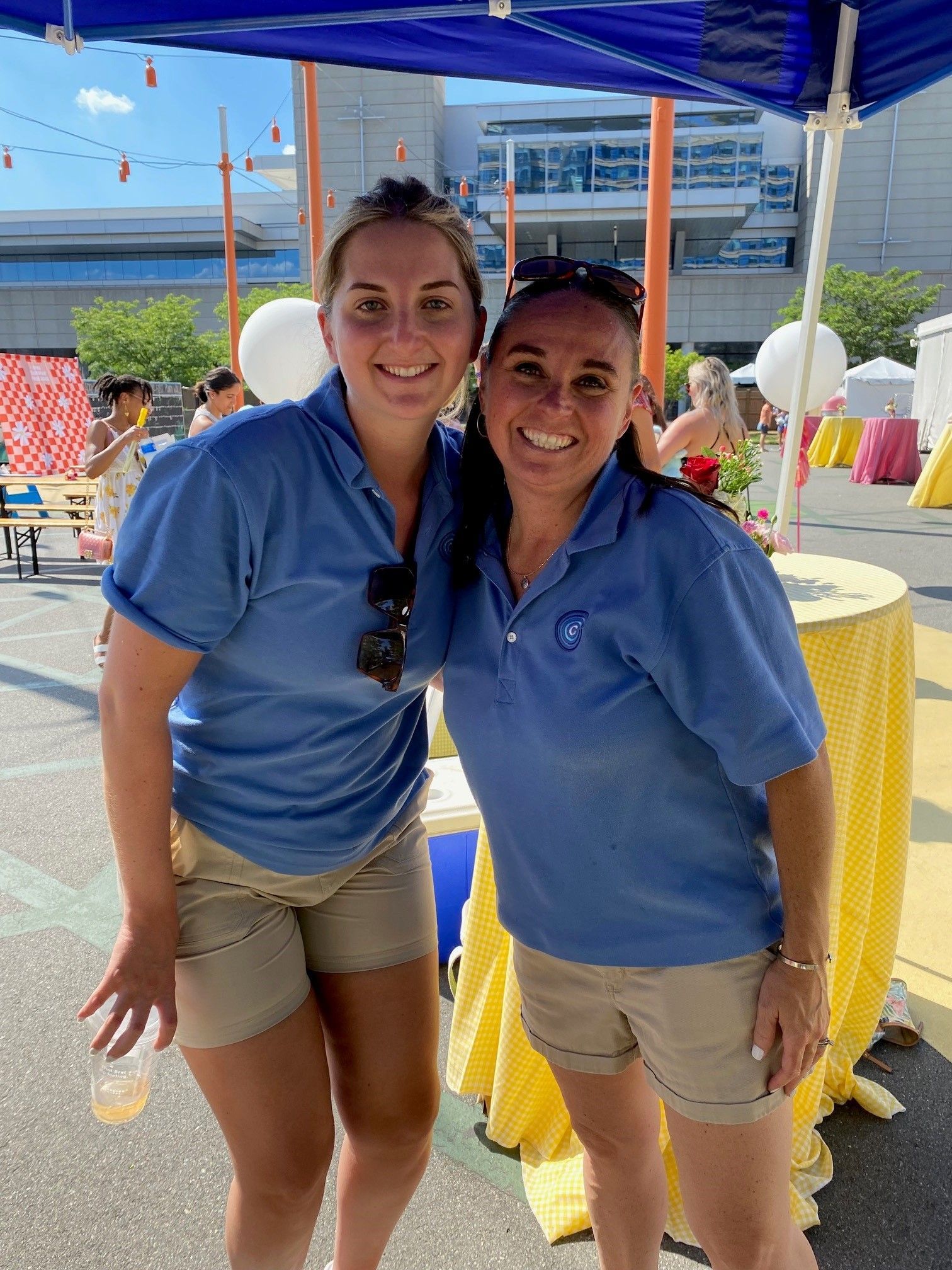 Two women are posing for a picture in front of a table.