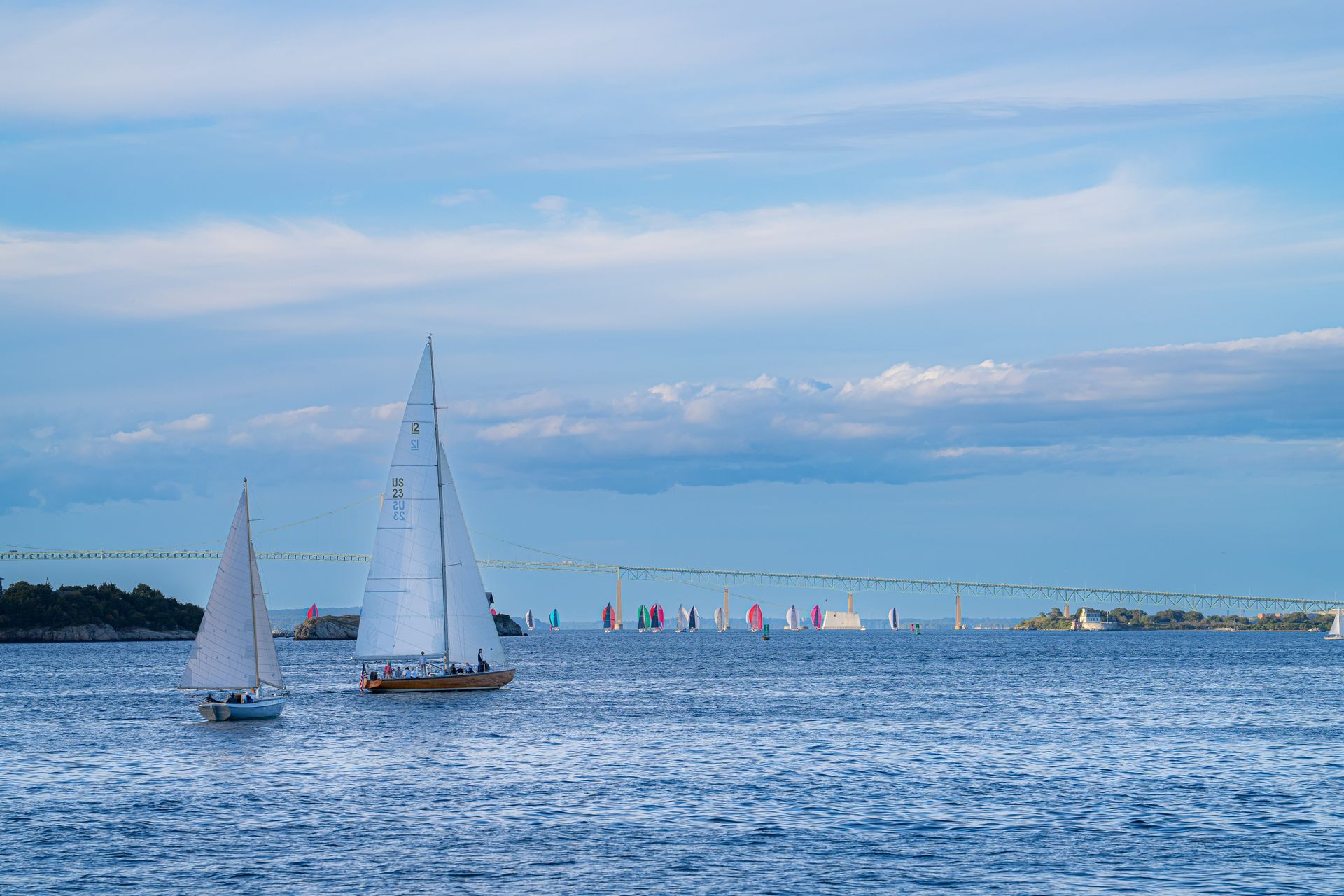 Sailboats on blue water under a cloudy sky.