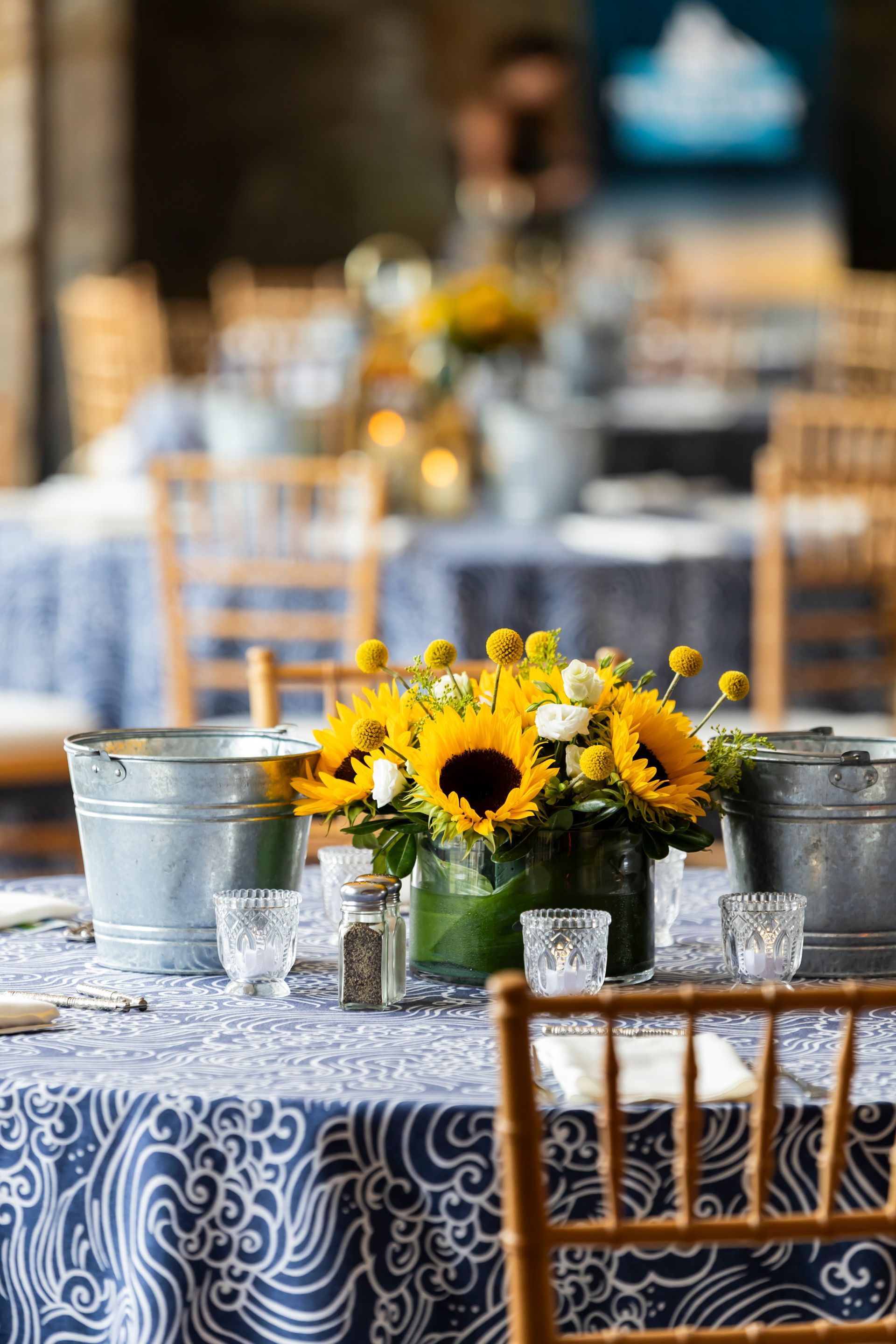 Table setting with sunflowers, navy and white tablecloths, metal buckets.
