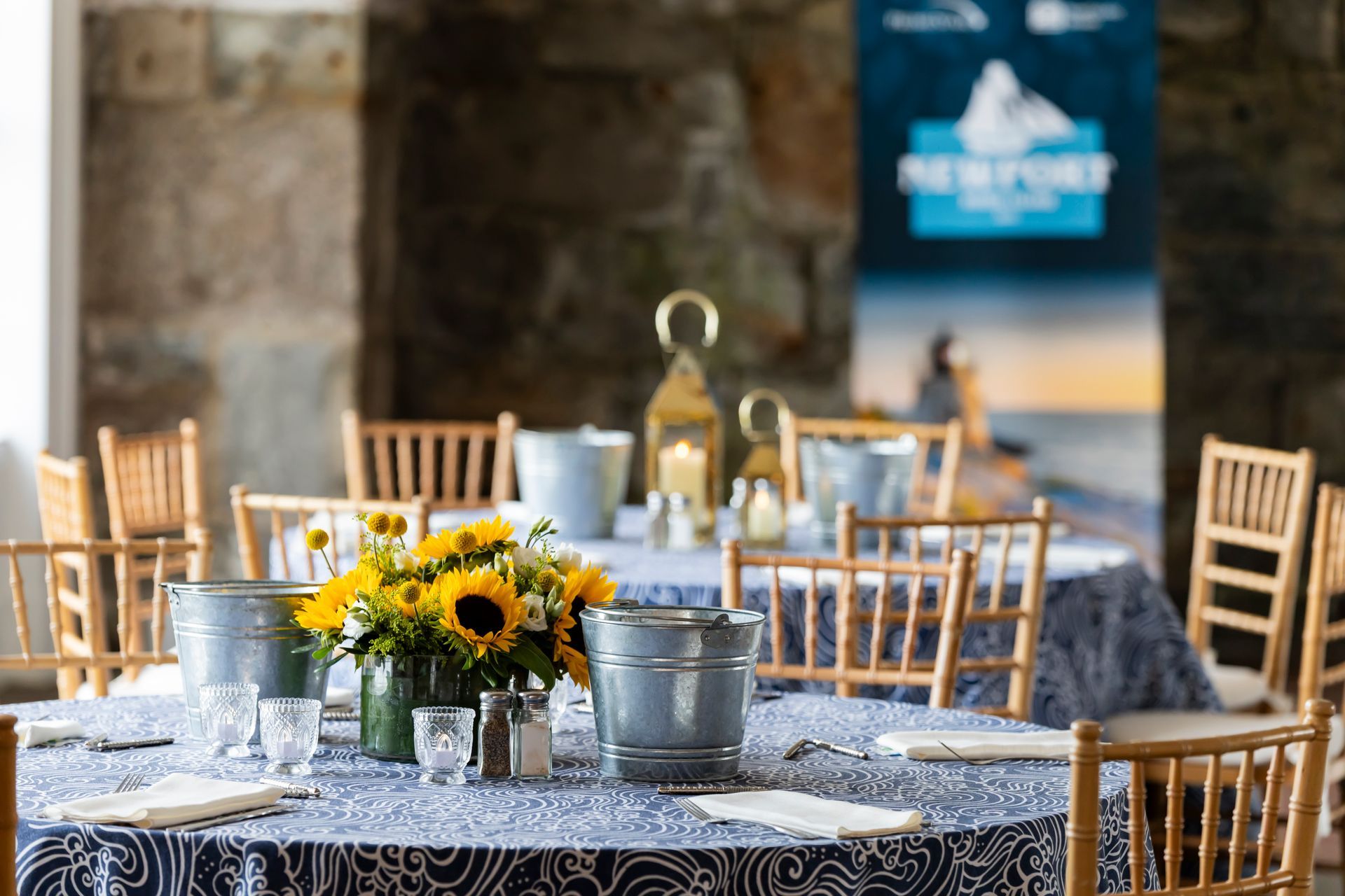 Round table set for a meal with sunflowers, blue accents, and a Newport banner.