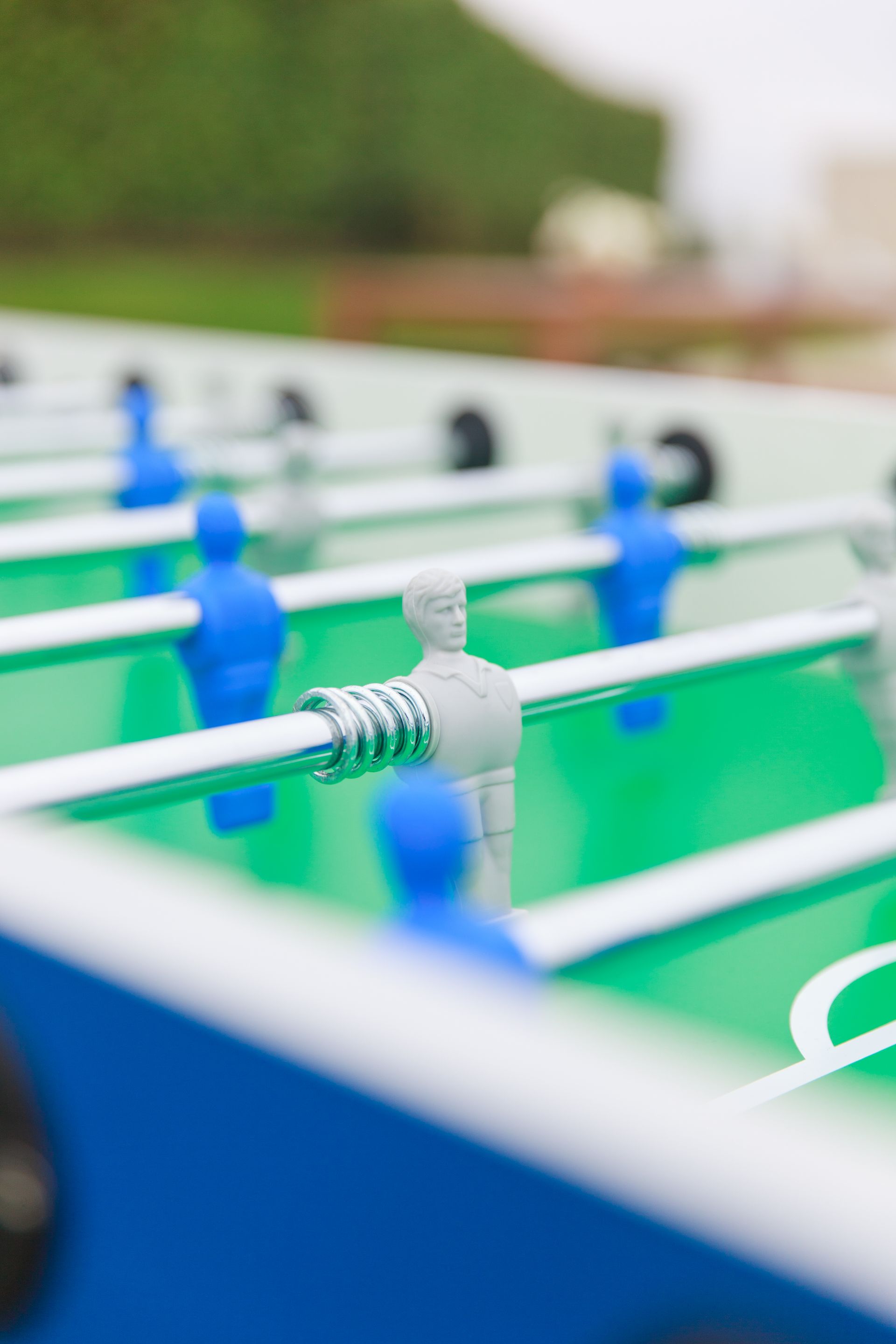 Close-up of a foosball table; blue and gray figures on green surface.