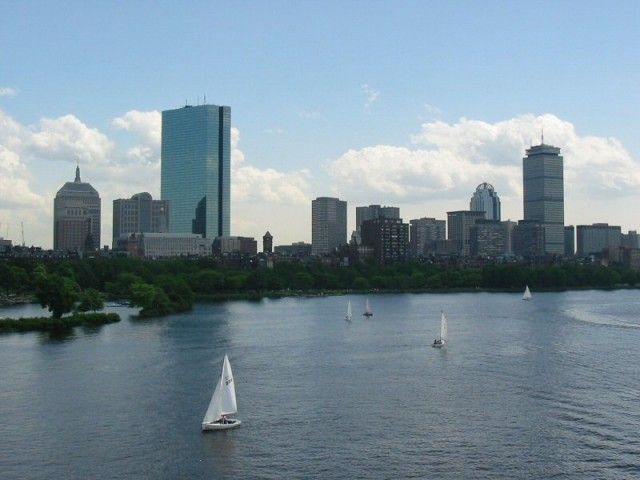 Boston skyline with sailboats on water. Blue sky and cloudy.