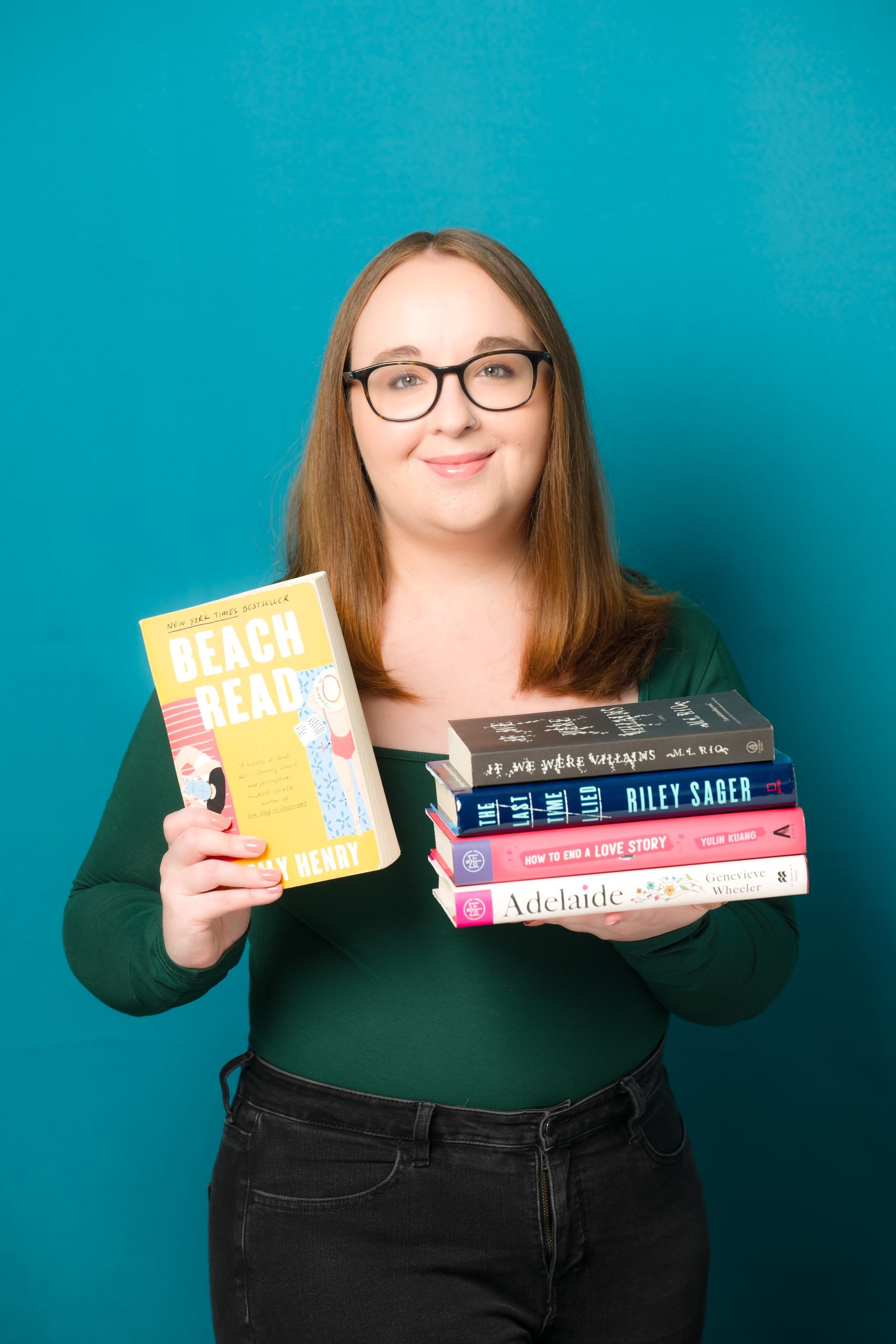 A woman is holding a stack of books in her hands.