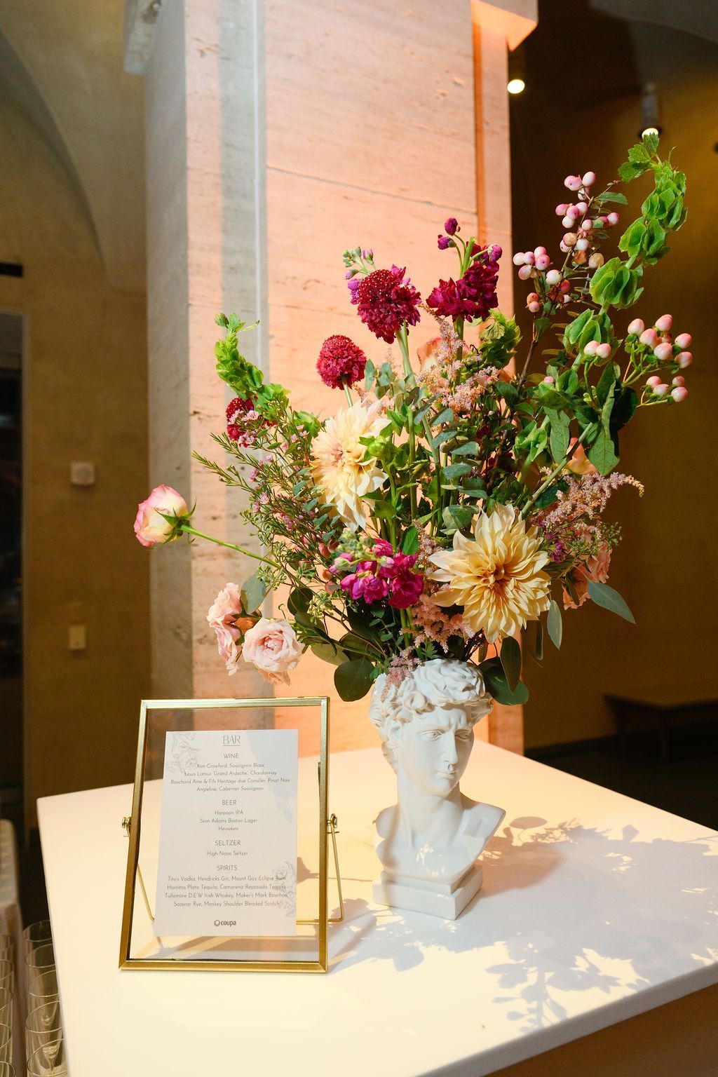 Floral arrangement in bust vase, table with framed menu.