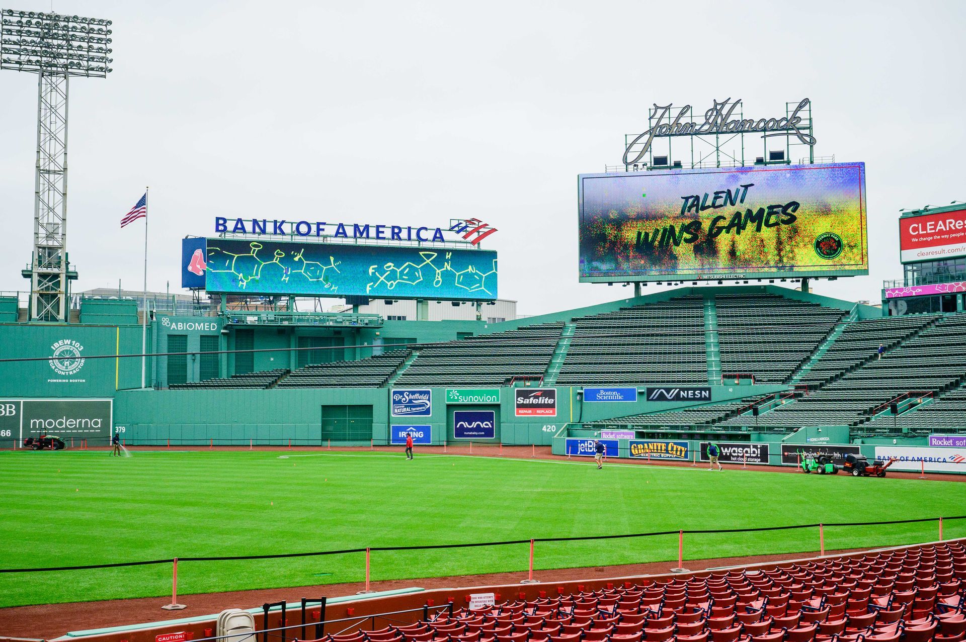 Empty Fenway Park with green field, red seats, and large signage for Bank of America and
