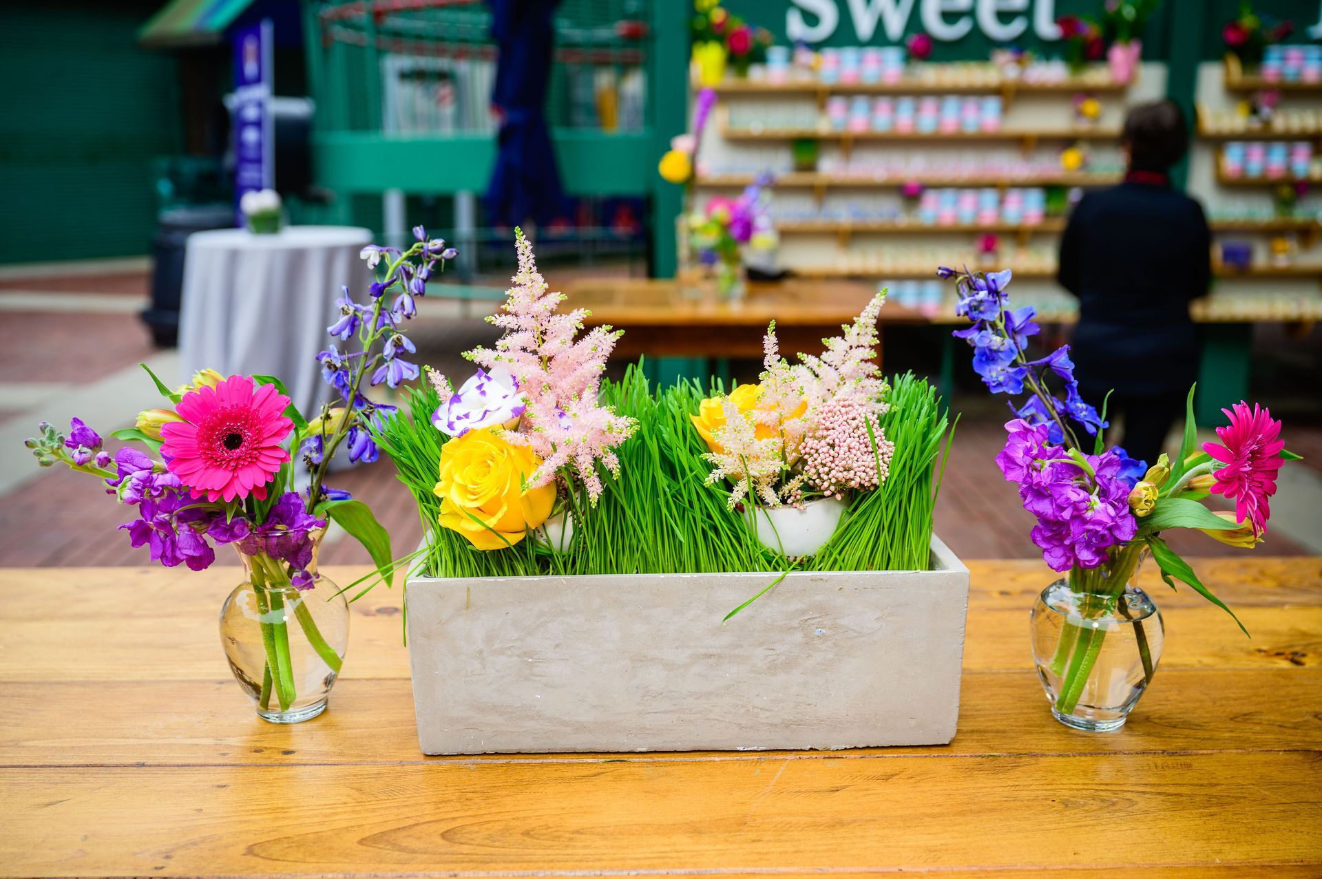 Floral arrangements with pink, purple, and yellow flowers on a wooden table.