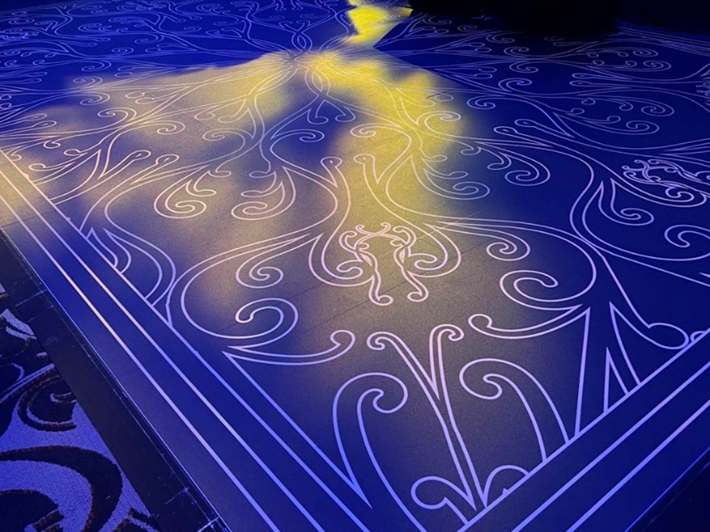 A blue carpet with a pattern on it and a light shining on it.