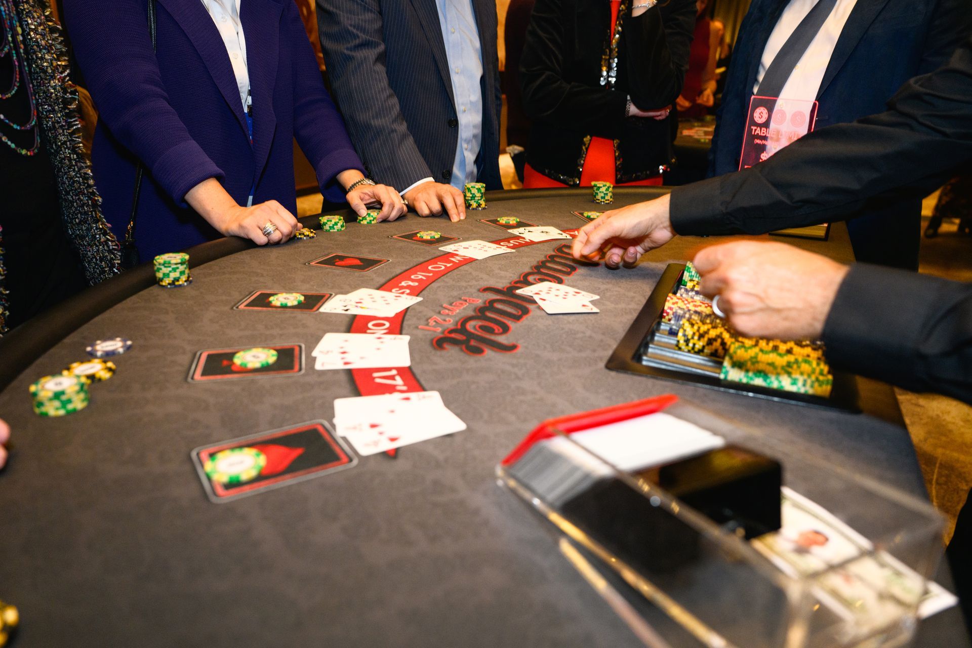 People playing blackjack at a table in a casino; cards and chips visible.