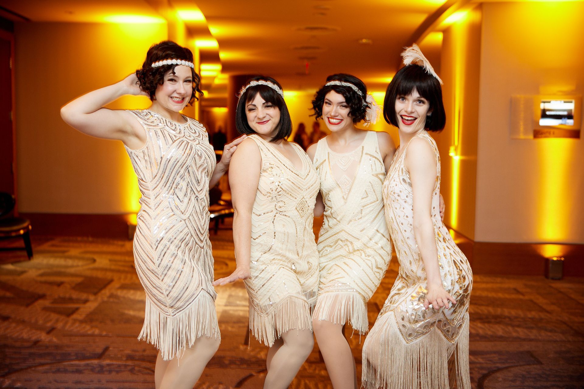 A group of women dressed in flapper dresses are posing for a picture.