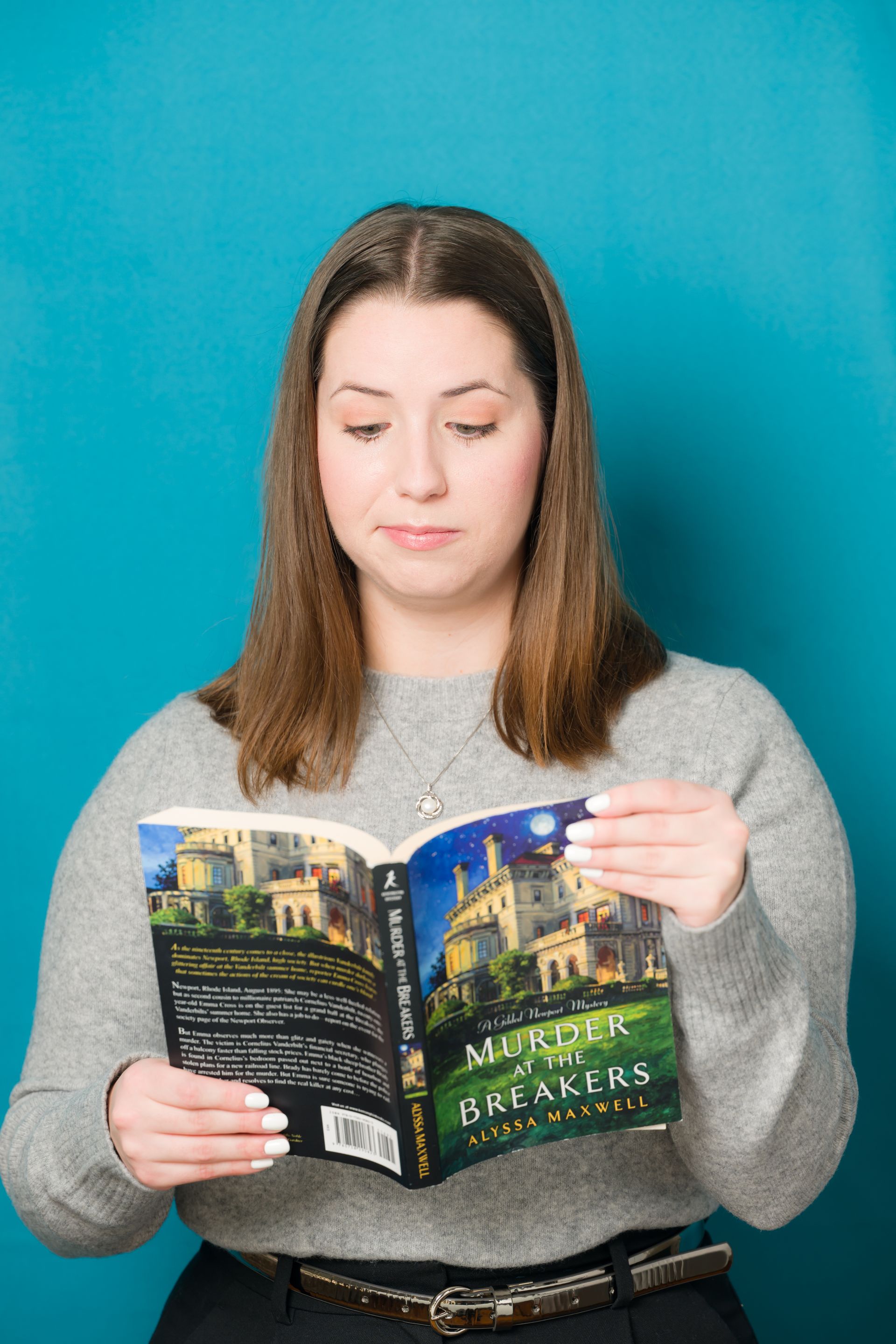 A woman is reading a book against a blue background.