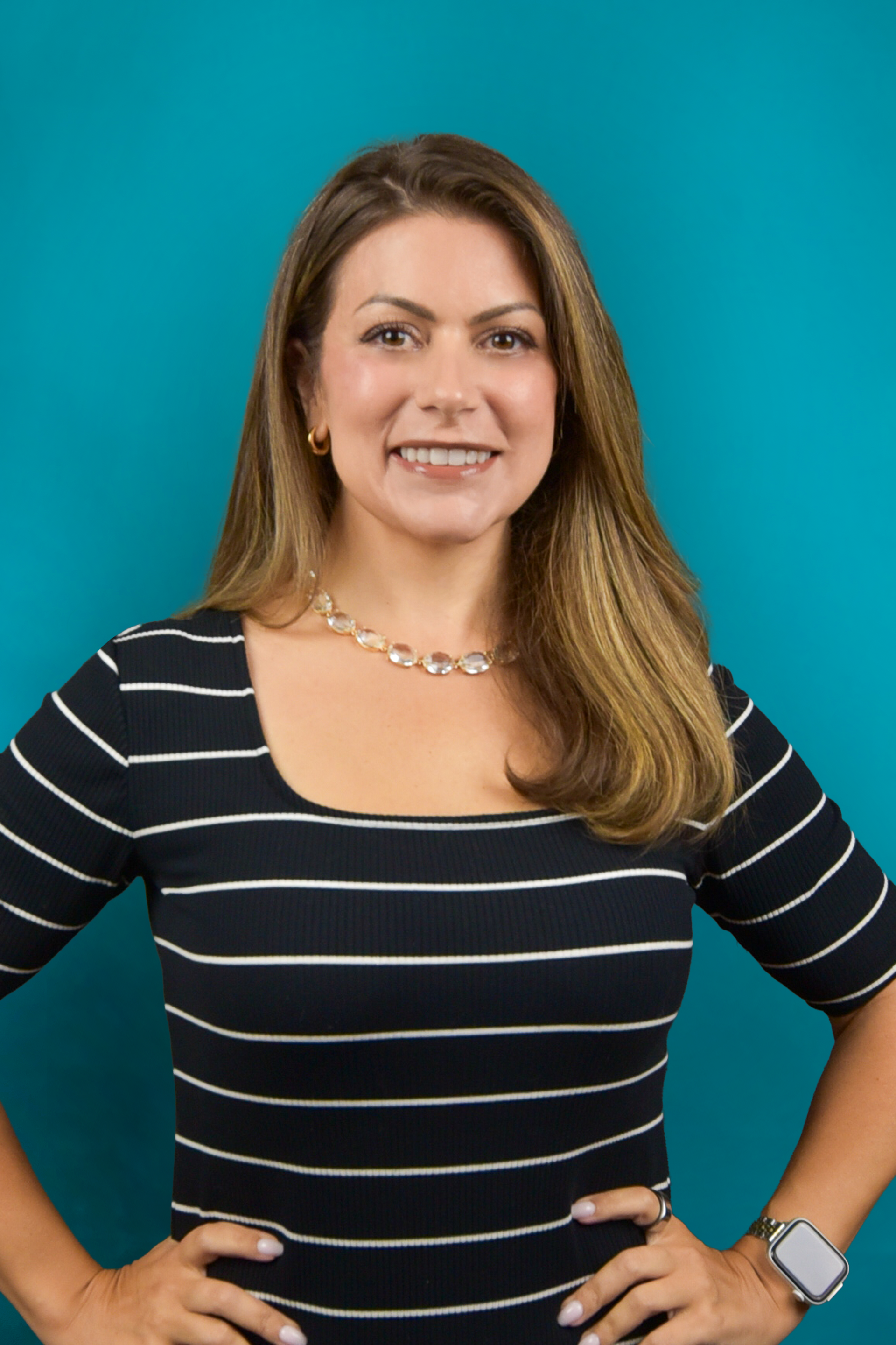 Smiling woman in a black-and-white striped top posing against a teal background