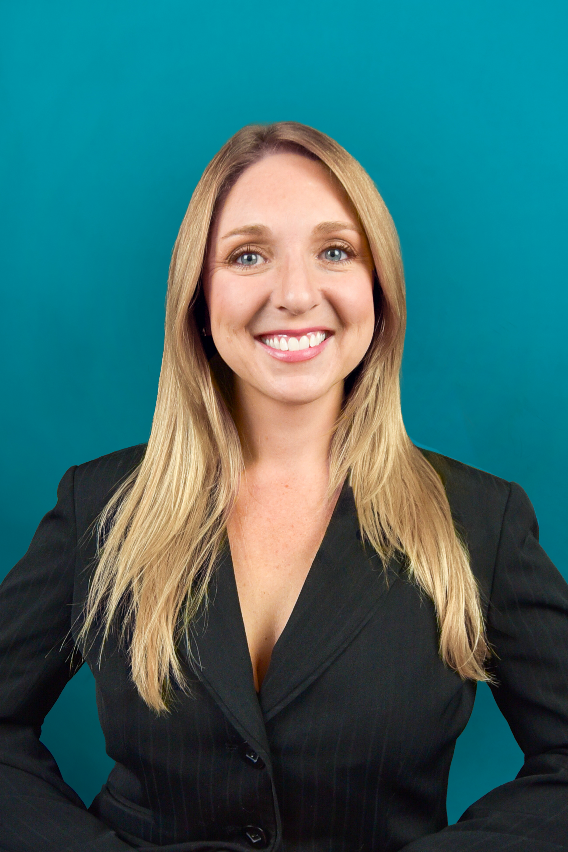Smiling woman in a black blazer posing against a teal background