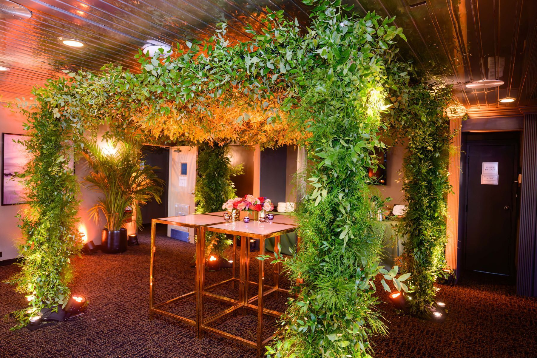 A room with tables and chairs surrounded by plants and leaves.