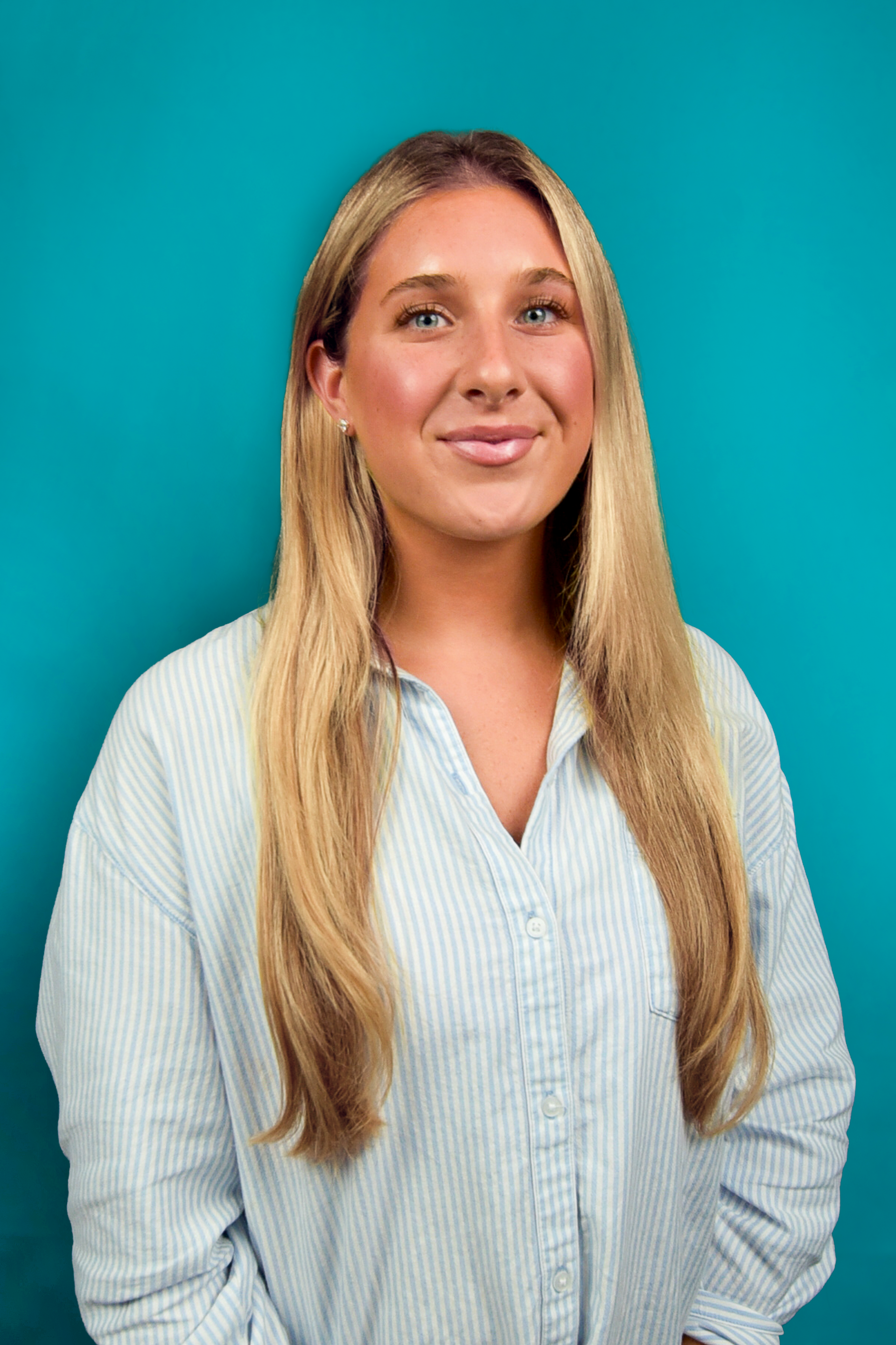 Woman standing against a teal background, wearing a light blue striped shirt, smiling at the camera.
