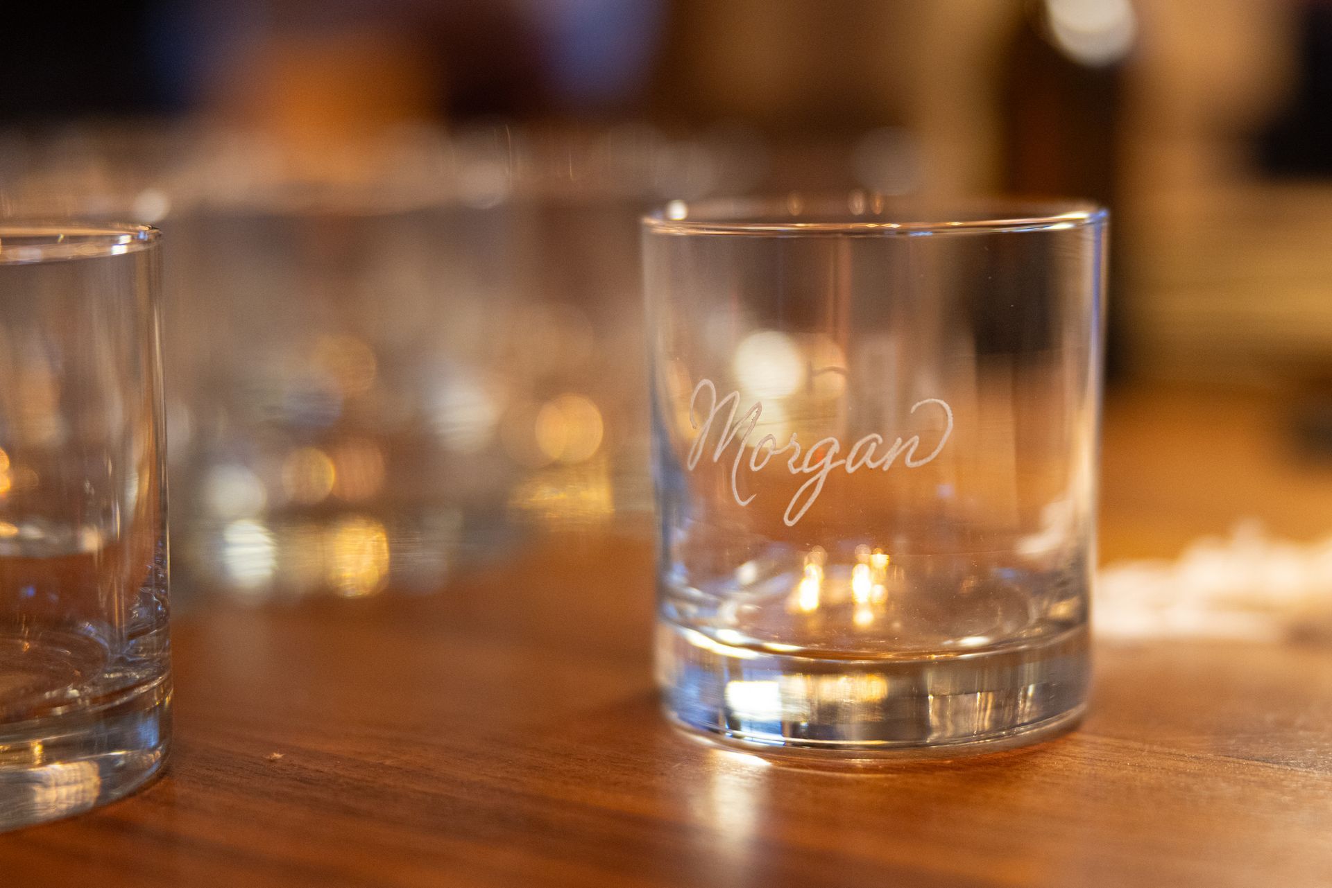 A glass with the name morgan on it is sitting on a wooden table.