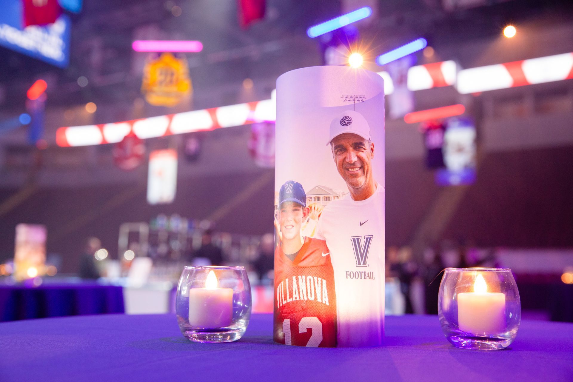 A purple table with two candles and a sign on it.