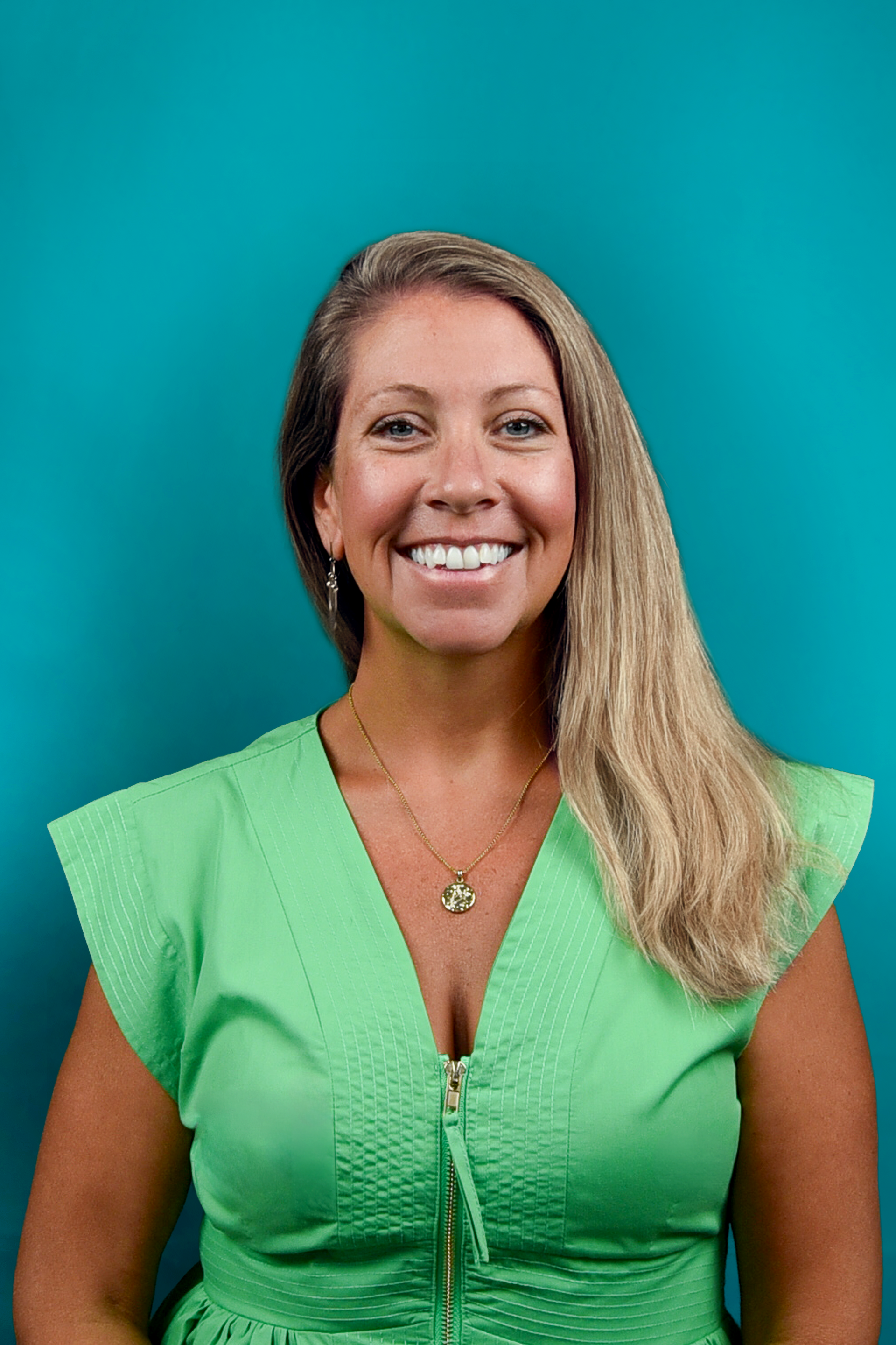 Smiling woman in a bright green blouse against a teal background