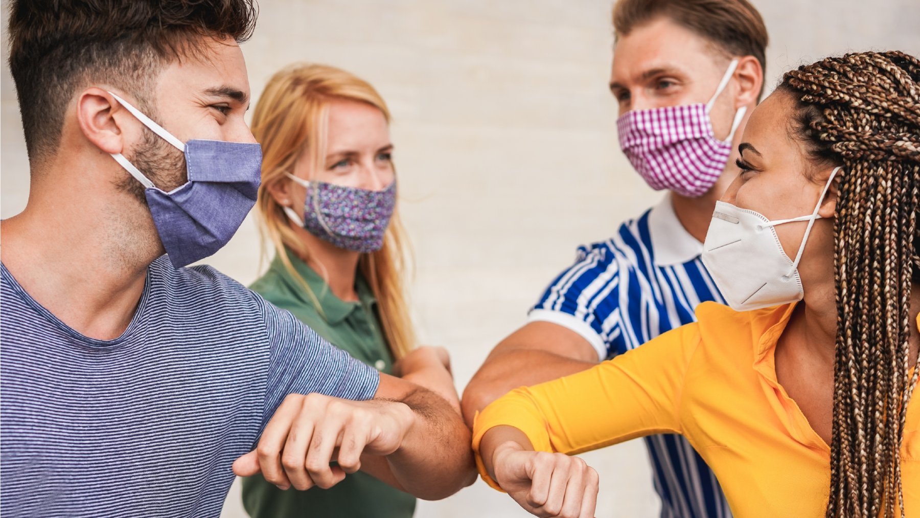 A group of people wearing face masks are giving elbow bumps.