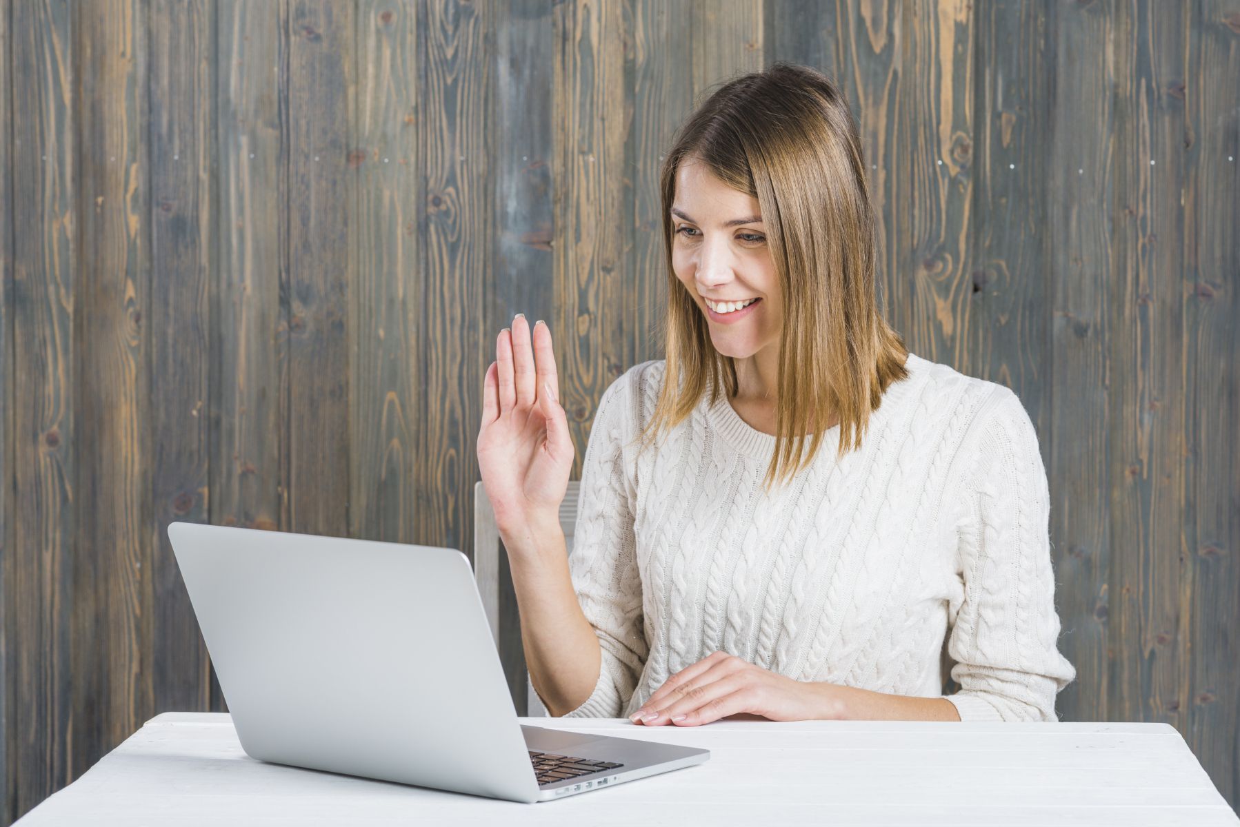 A woman is sitting at a table using a laptop computer.