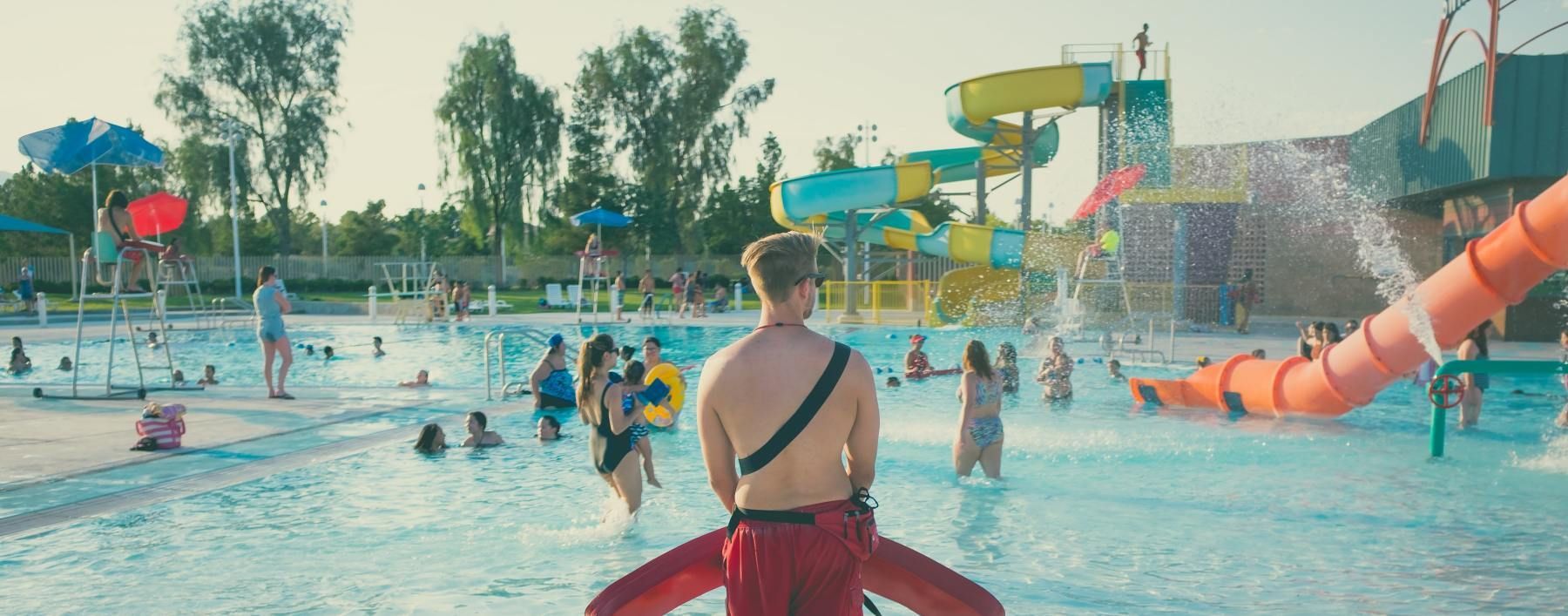 A lifeguard is standing in a swimming pool at a water park.