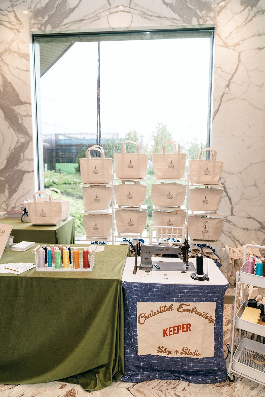 A display of tote bags with a sewing machine at a crafts fair.