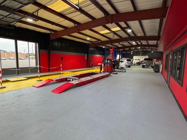 Empty industrial workshop with red walls, steel beams, and equipment on a gray floor | Coastal Autoxpress
