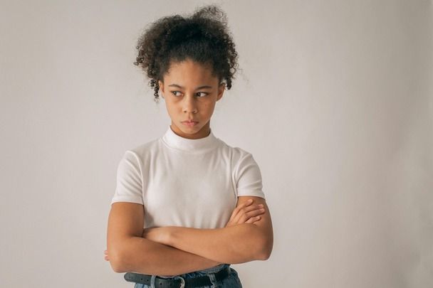 A young woman is standing with her arms crossed and looking at the camera.