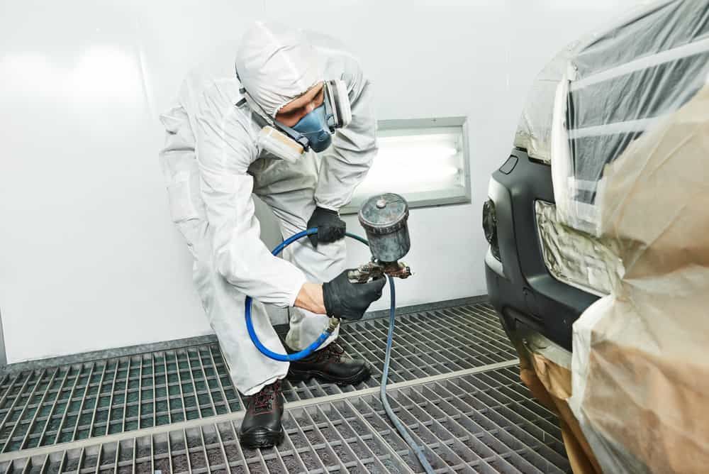 A Man In A Protective Suit Is Painting A Car In A Paint Booth — Mahers Smash Repairs In Barraba, NSW