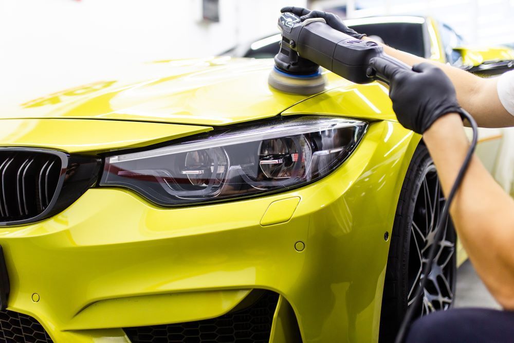 A Man Is Polishing a Yellow Car — Mahers Smash Repairs in Gingers Creek, NSW