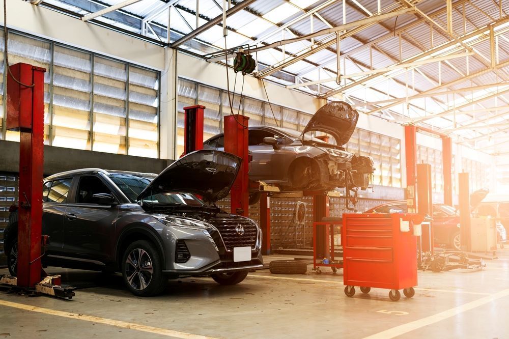 Two Cars Are Sitting on A Lift in A Garage — Mahers Smash Repairs in Barraba, NSW