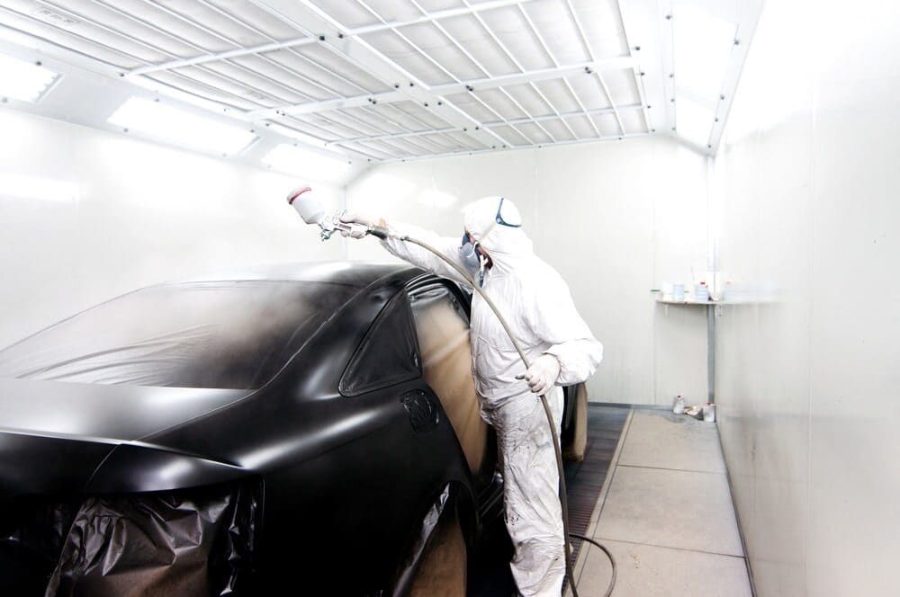 A Man Is Spray Painting A Car In A Paint Booth — Mahers Smash Repairs in Tamworth, NSW