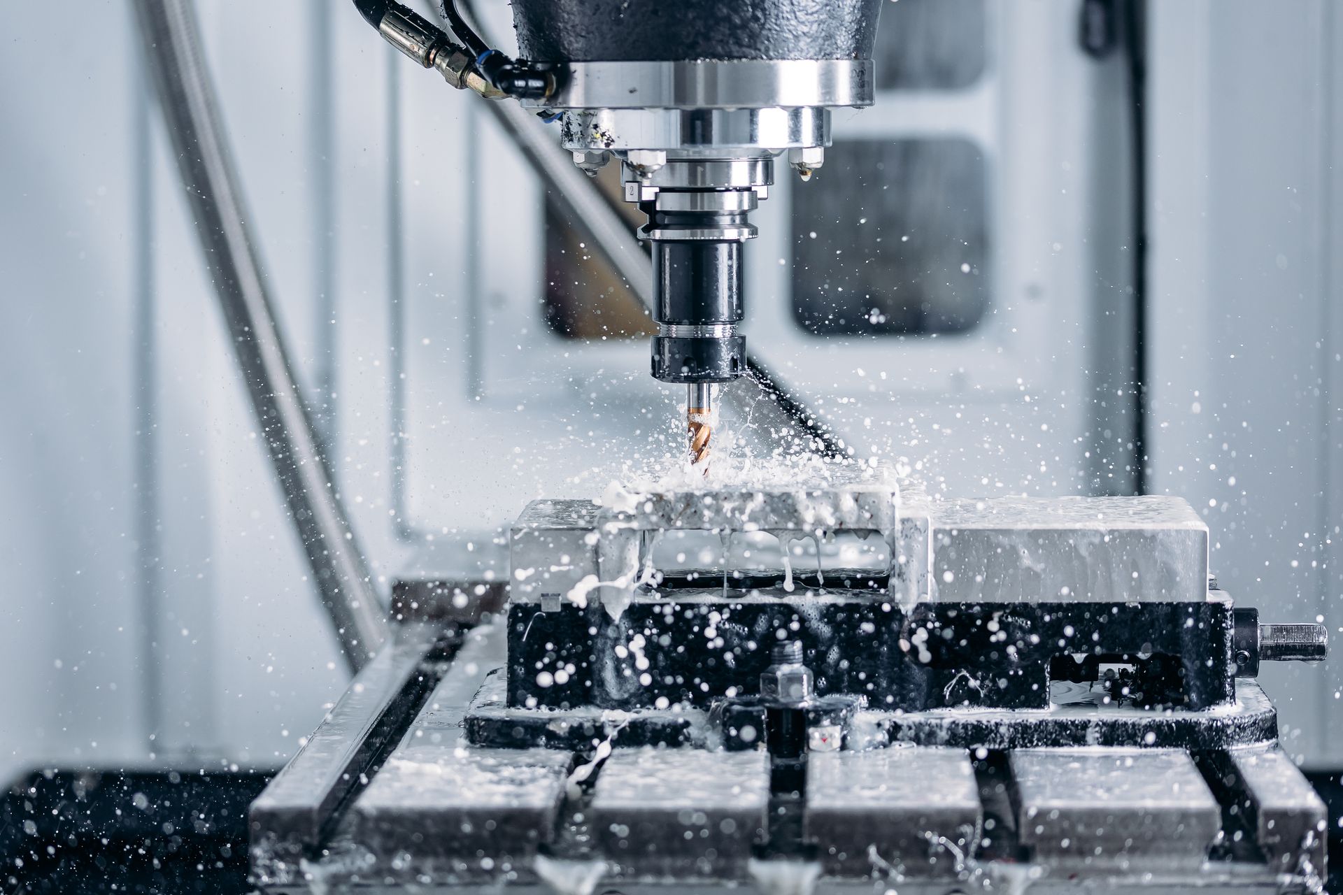 CNC machine cutting metal with coolant spraying as the tool shapes the workpiece.