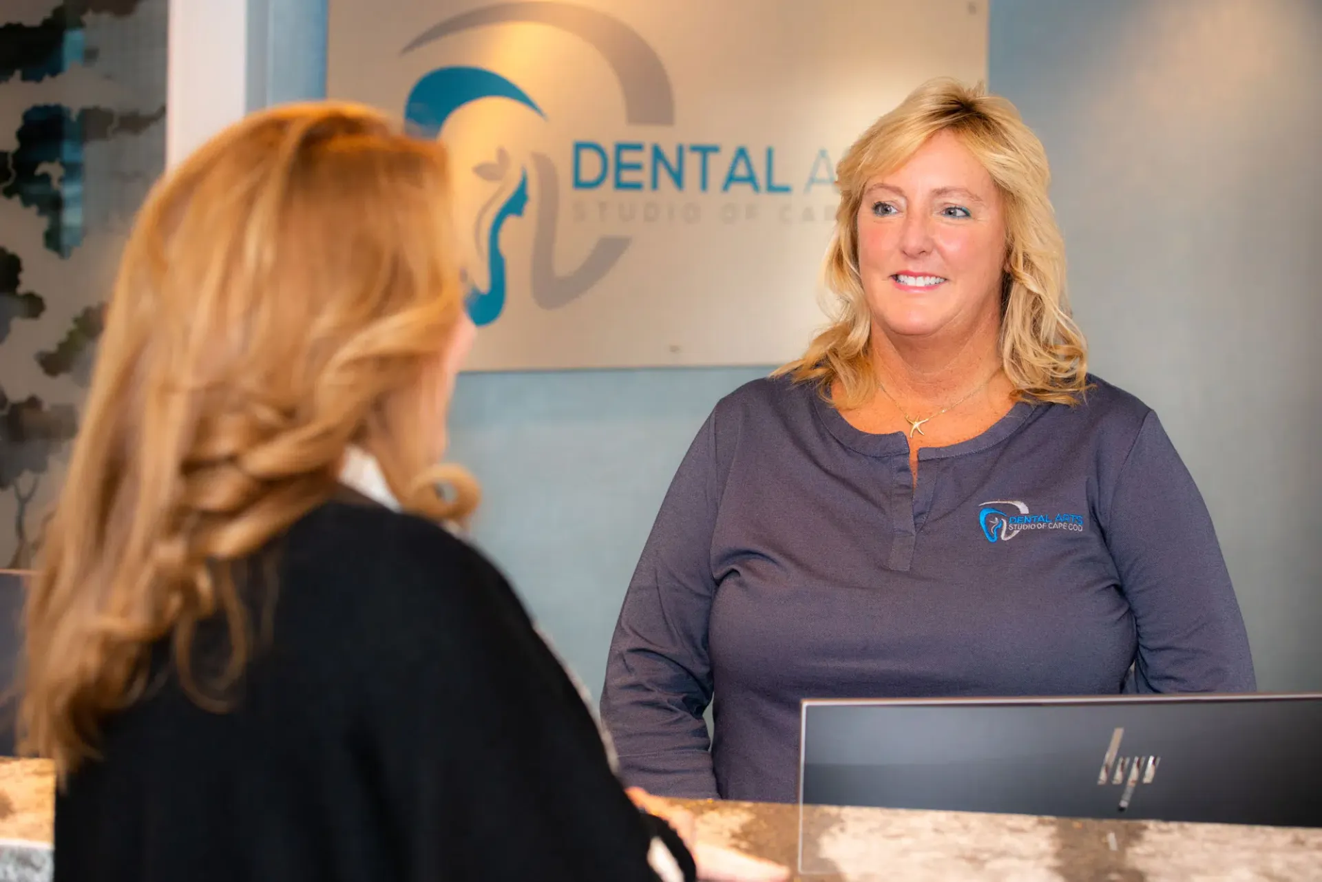 Dental office reception desk with a smiling staff member greeting a visitor