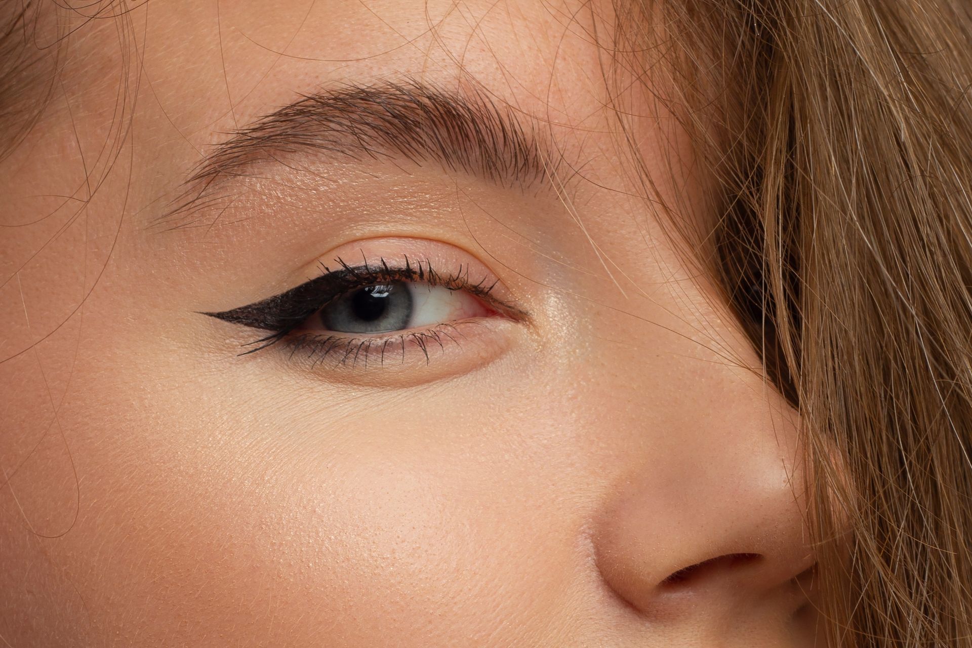 Close-up of a face with winged eyeliner and a soft smile