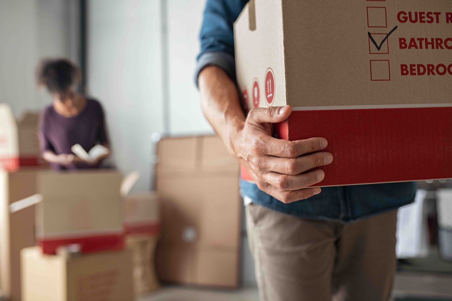 A man is carrying a cardboard box in a room.