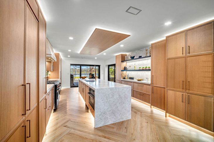 Modern kitchen with wood cabinetry, marble island, and bright natural light