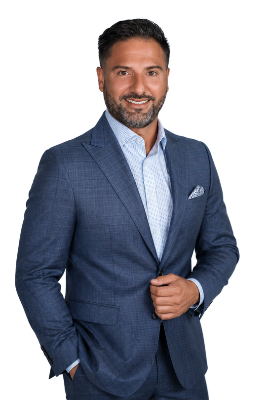 Man in a blue suit jacket posing against a white background, with one hand in his pocket.