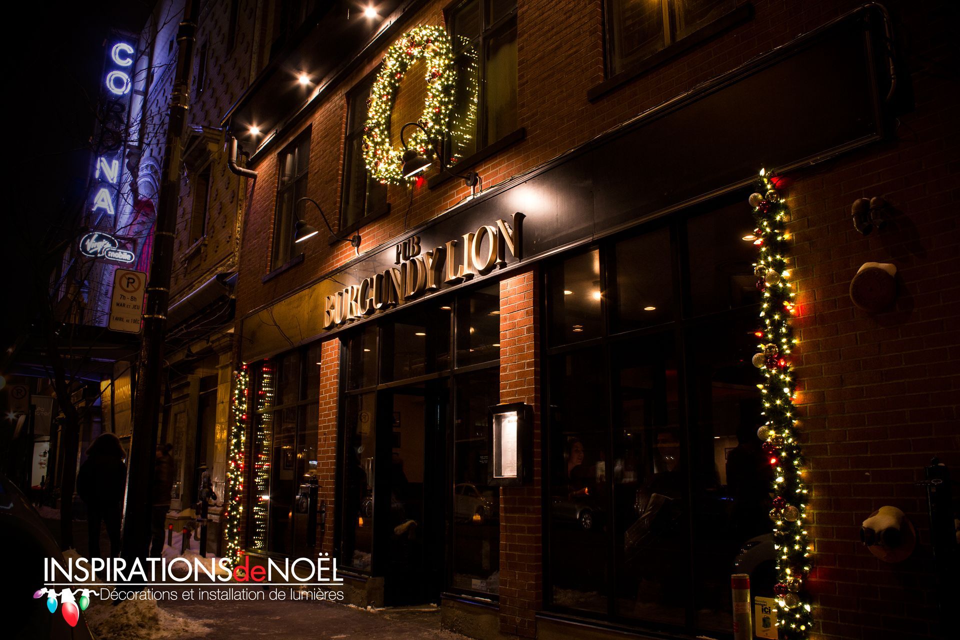 Extérieur du restaurant la nuit, décoré de lumières de Noël et d'une couronne. Façade en briques avec enseigne « À L'ANTIQUE ».