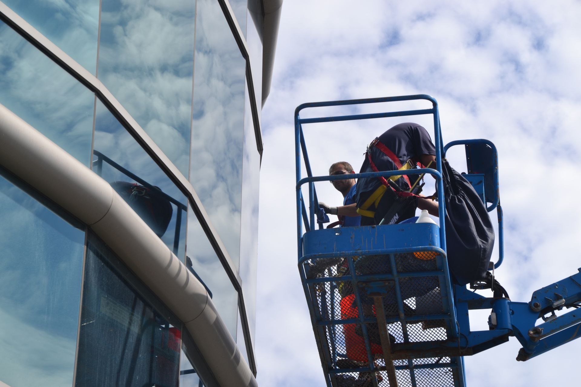 Two men are cleaning a building with a crane