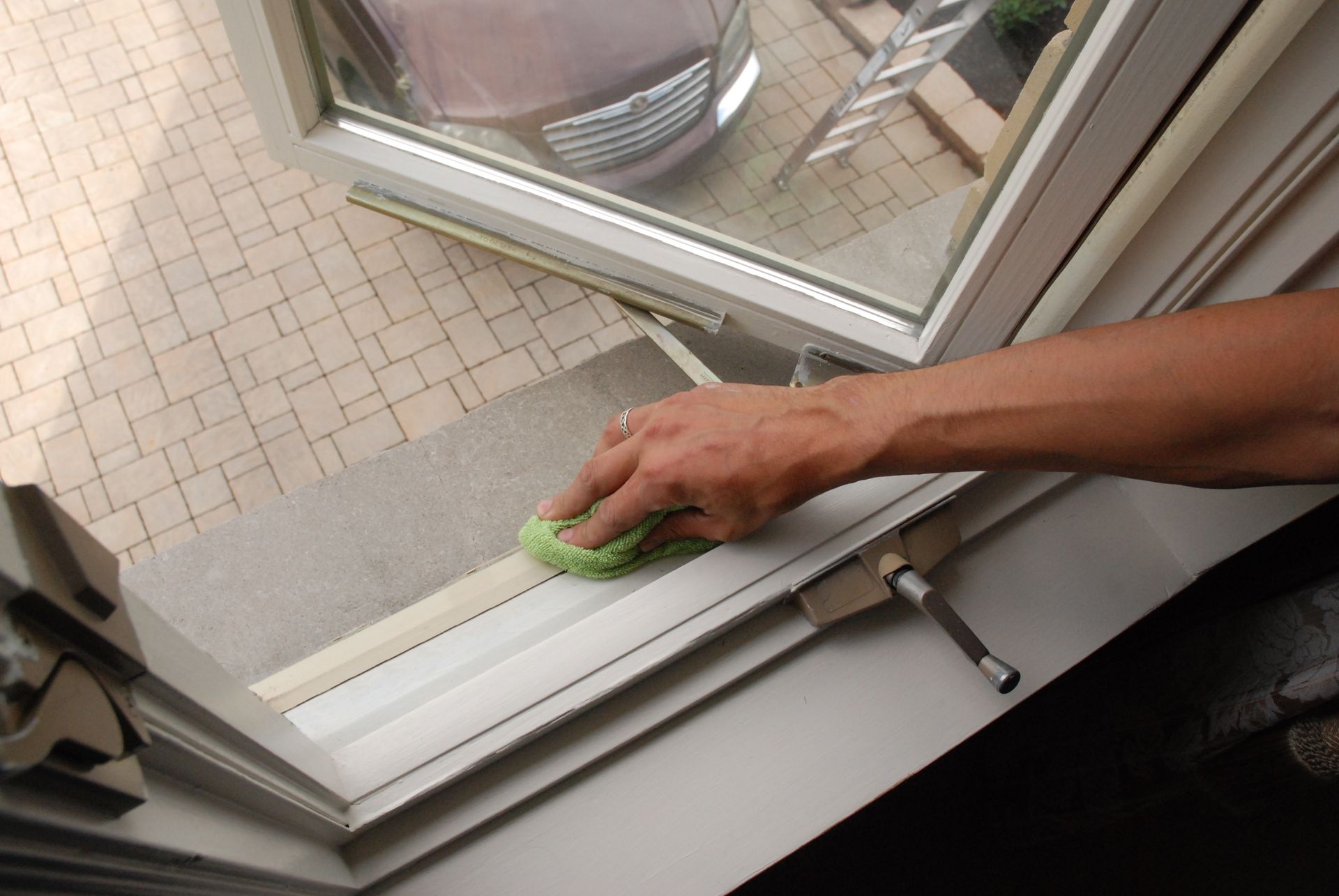 A person is cleaning a window with a green sponge