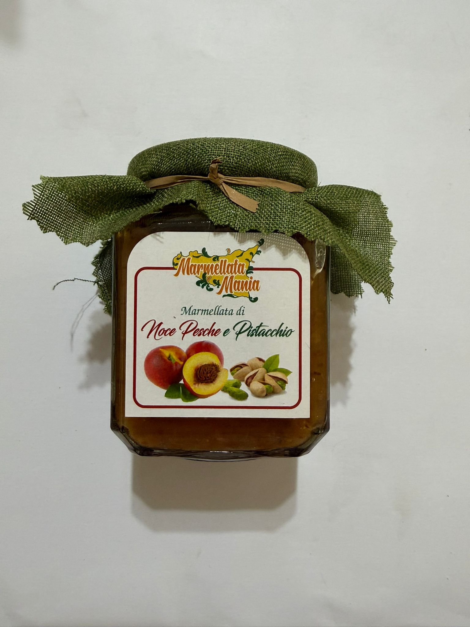Barattolo decorativo con coperchio a forma di foglia verde ed etichetta con frutta su sfondo bianco.