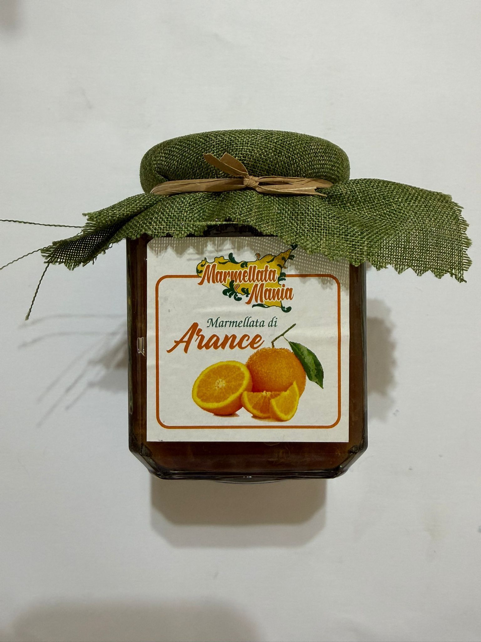 Barattolo al gusto d'arancia con coperchio in tessuto decorativo verde ed etichetta a forma di fetta d'arancia.