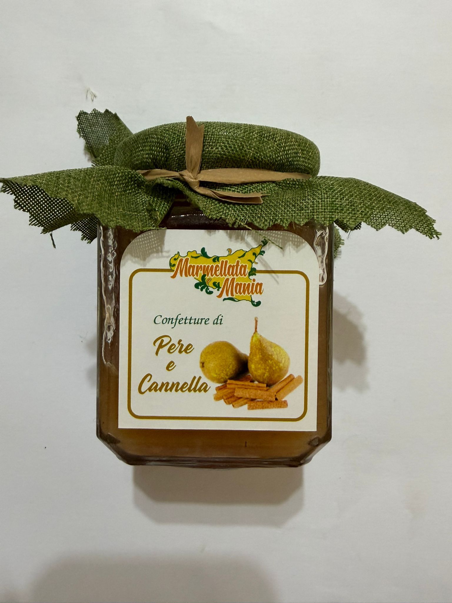 Candela in barattolo di vetro quadrato con decorazione a foglie verdi ed etichetta con la scritta 
