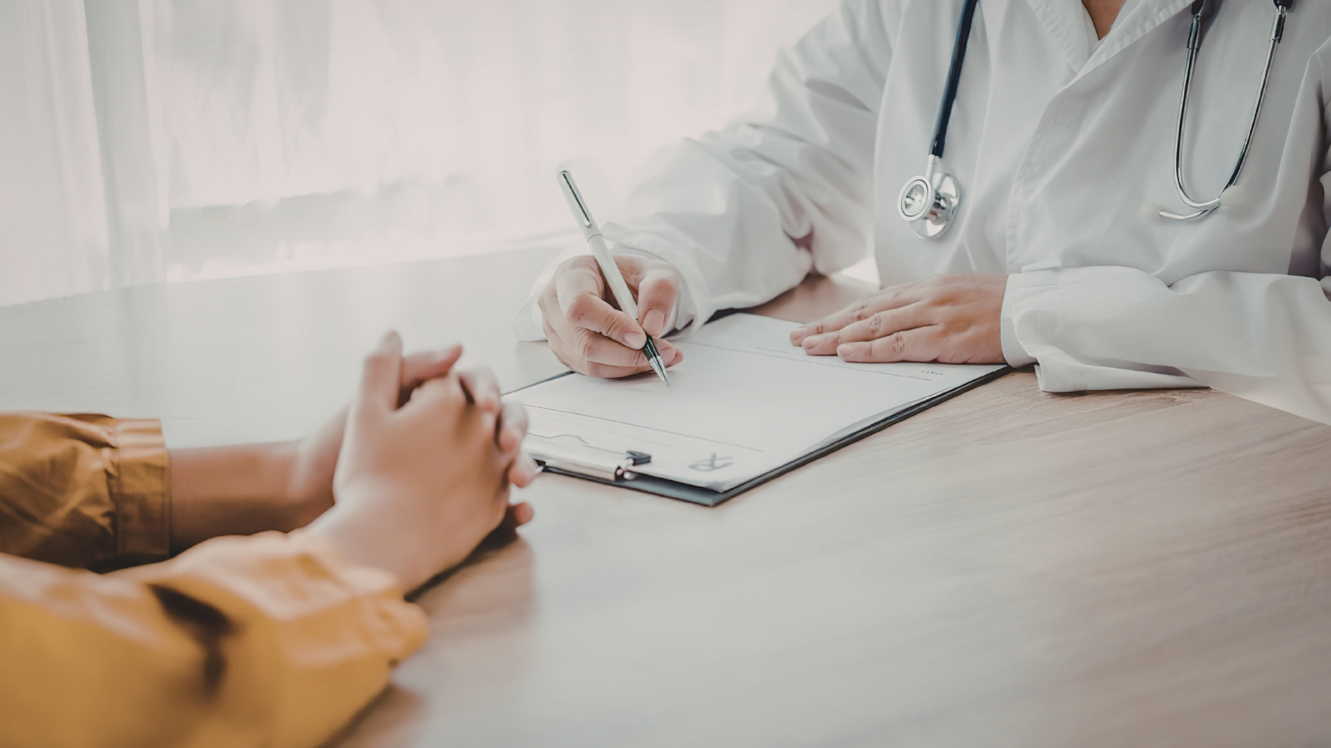 Doctor taking notes during a consultation with a patient at a desk