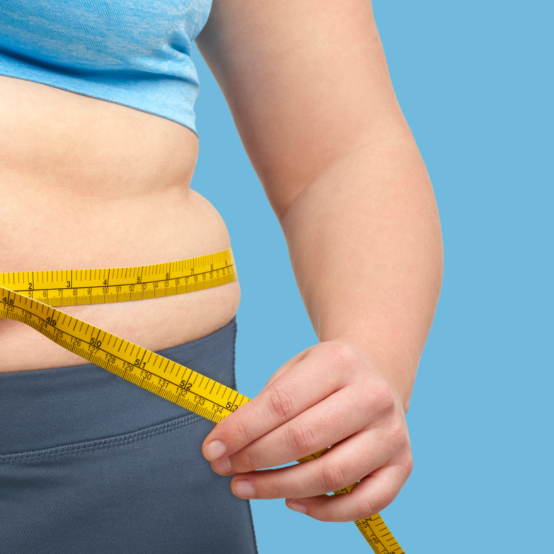 A woman is measuring her waist with a tape measure