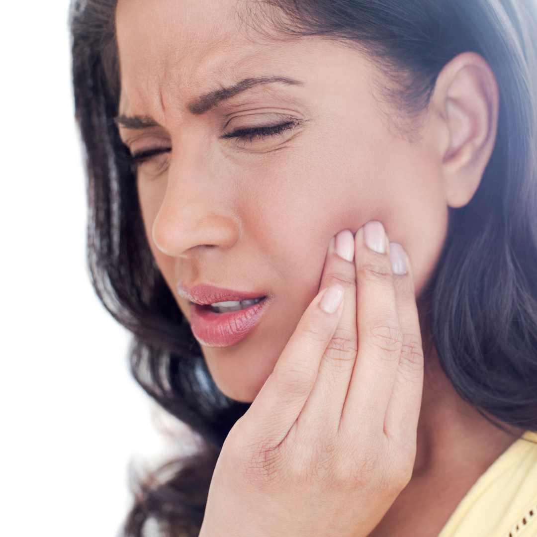 A woman is holding her face in pain because of a toothache